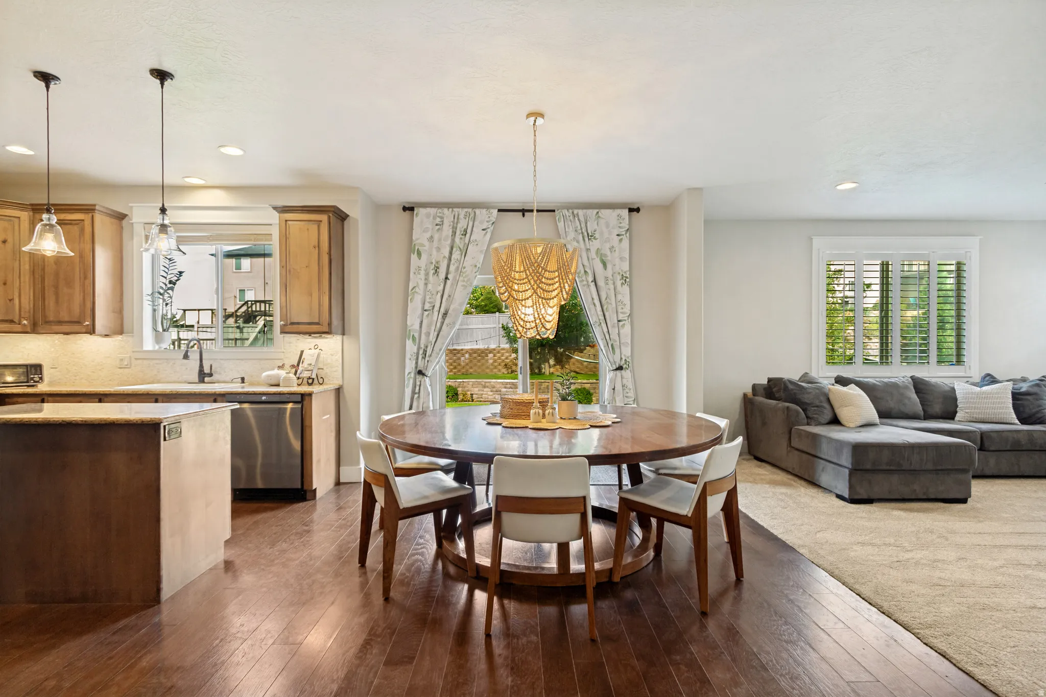 Open-concept living area with wood-finish flooring, recessed lighting, and a white shuttered window