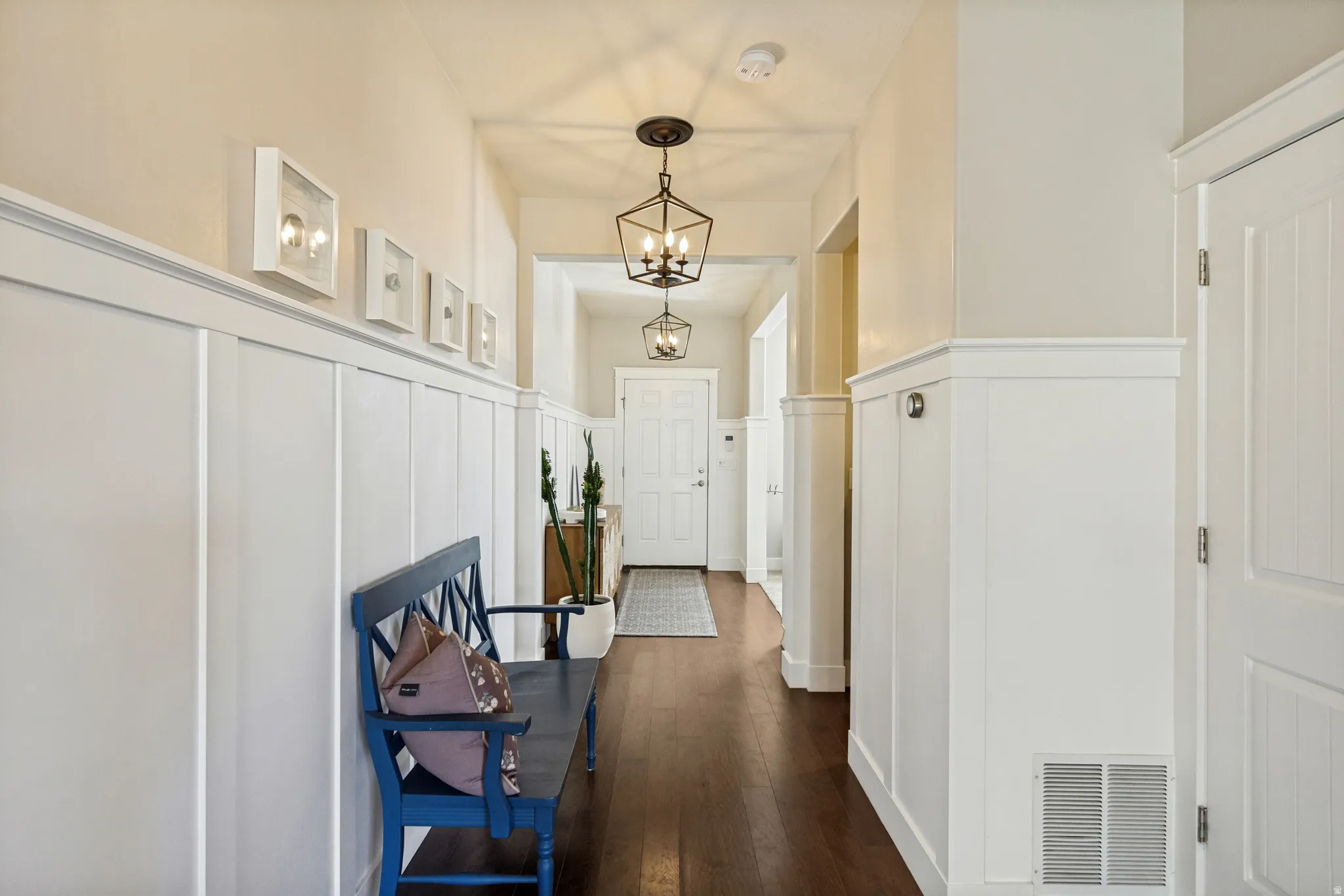 Hardwood flooring, wainscoting, recessed wall lighting, paneled doors, and ceiling-mounted light fixtures