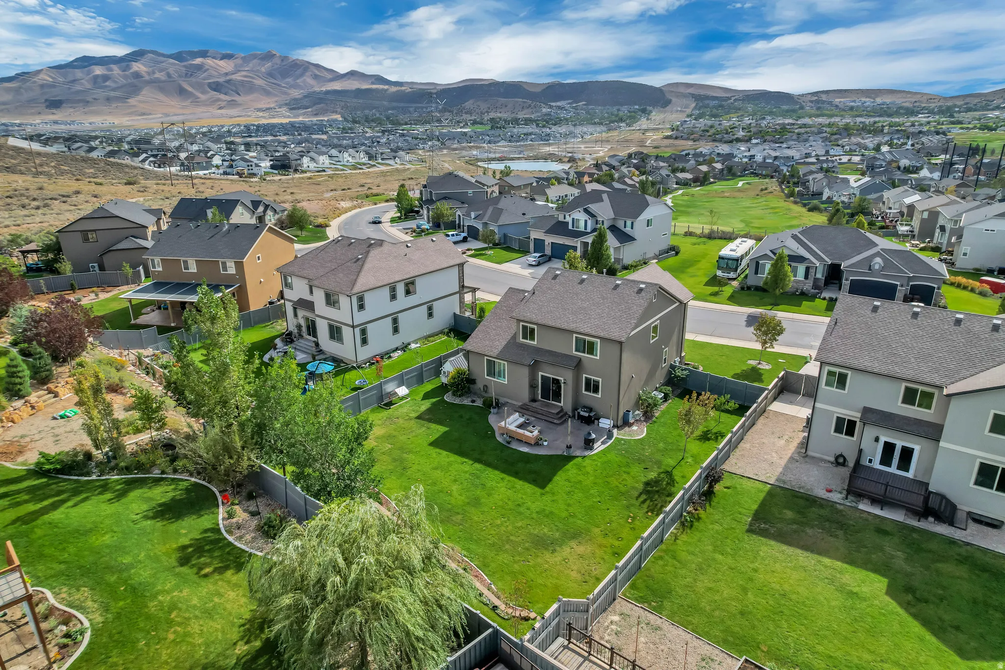 Expansive backyard featuring a manicured lawn, paved patio, and mature landscaping