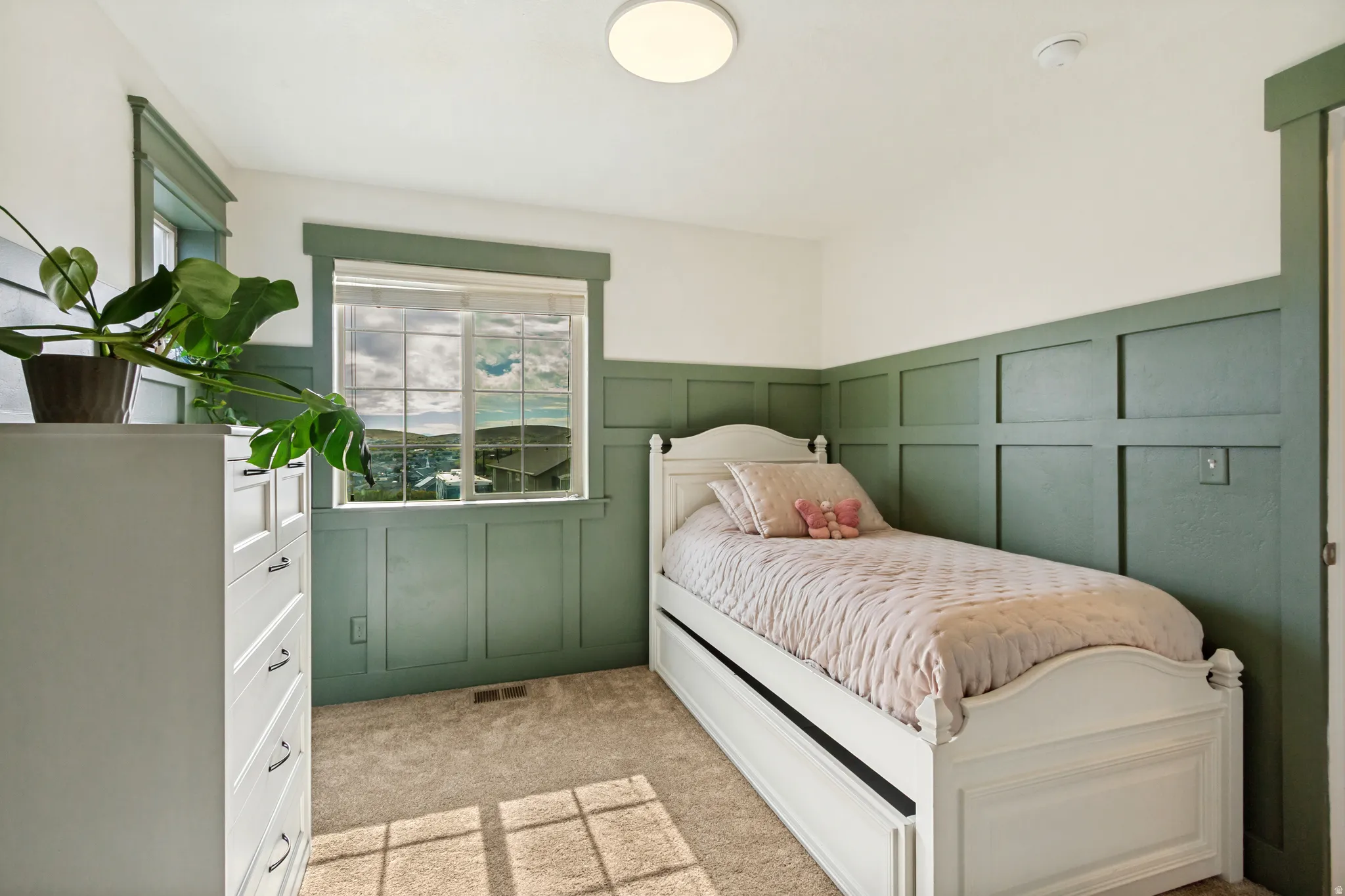 Carpeted room featuring a window with a mountain backdrop, a flush-mount ceiling light, and board and batten wall detailing