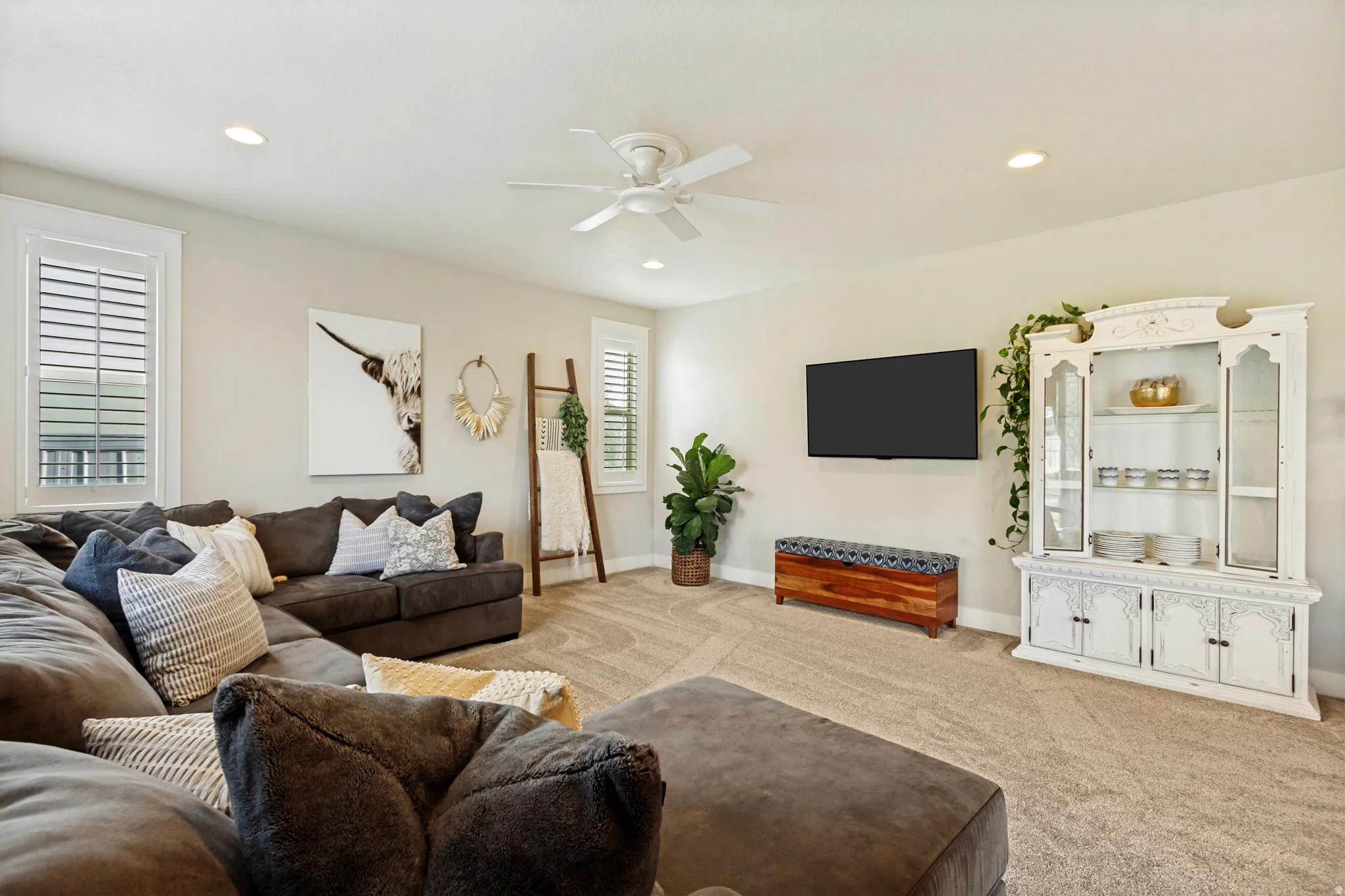 Recessed lighting, ceiling fan, neutral carpet flooring, and white plantation shutters on multiple windows