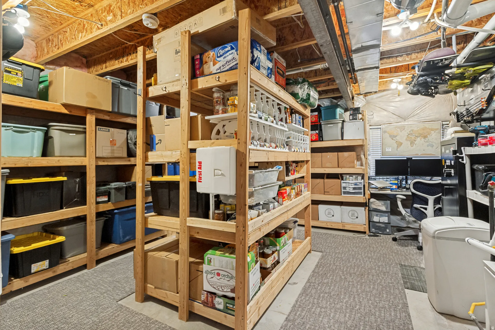 Extensive built-in wood shelving for storage, exposed ceiling joists, and carpeted flooring