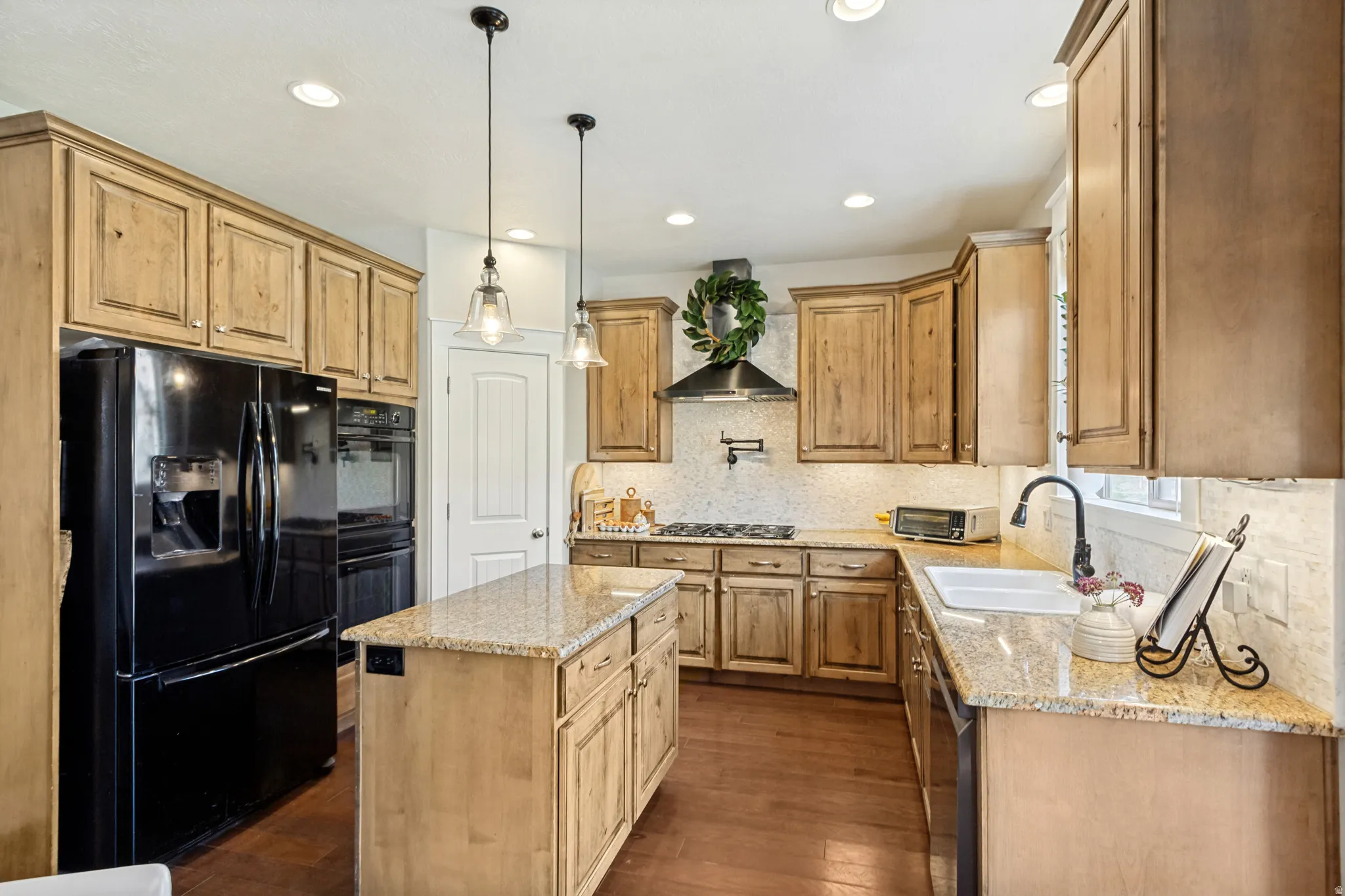 Kitchen featuring wood cabinetry, granite countertops, tile backsplash, a center island, and wood-finish flooring