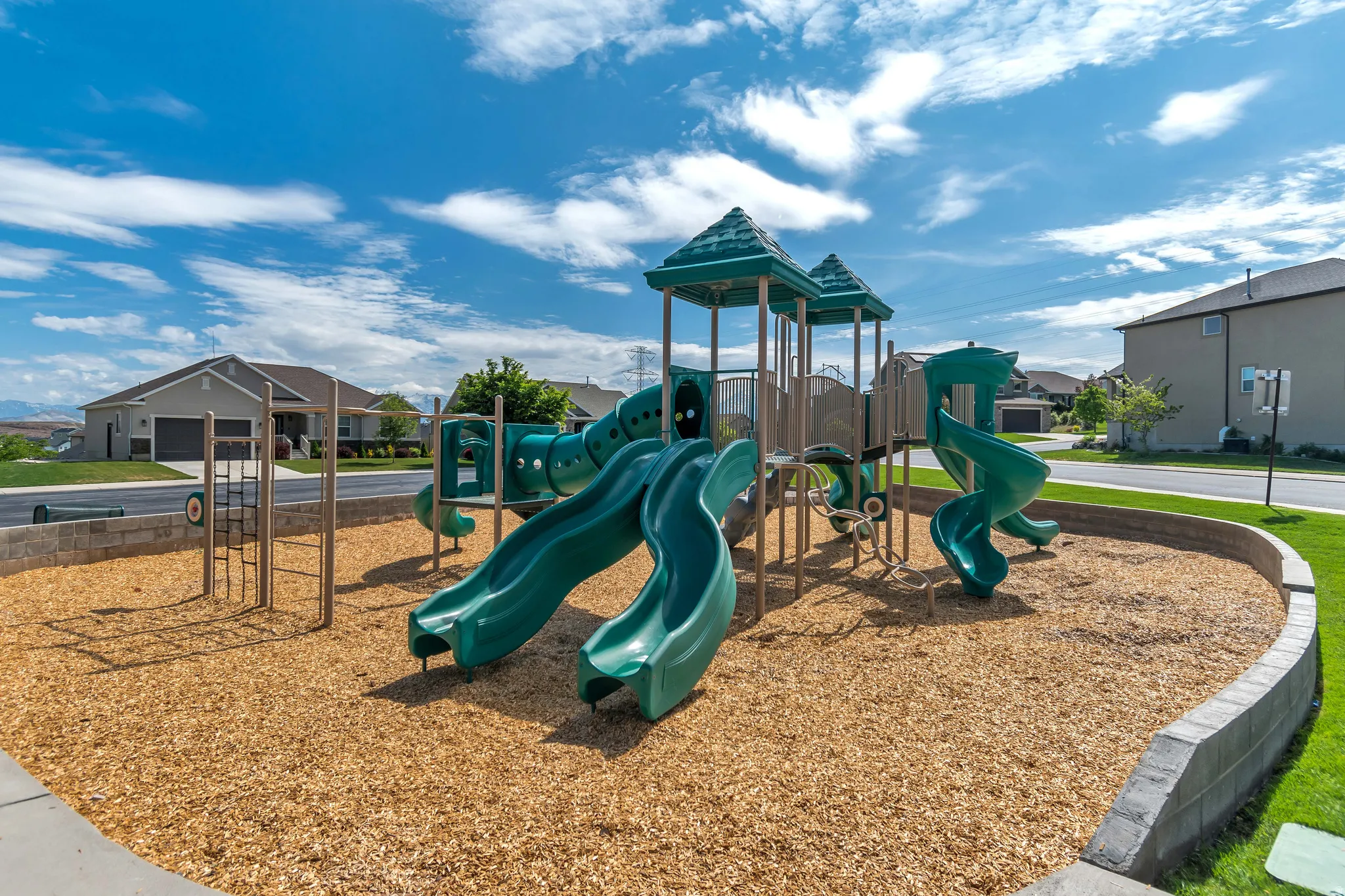 Community playground with multiple slides, climbing structures, and a wood chip base