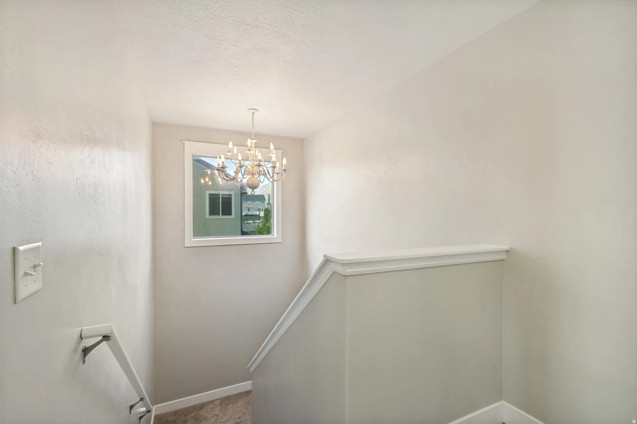 Chandelier lighting, framed window, white trim, and a carpeted staircase