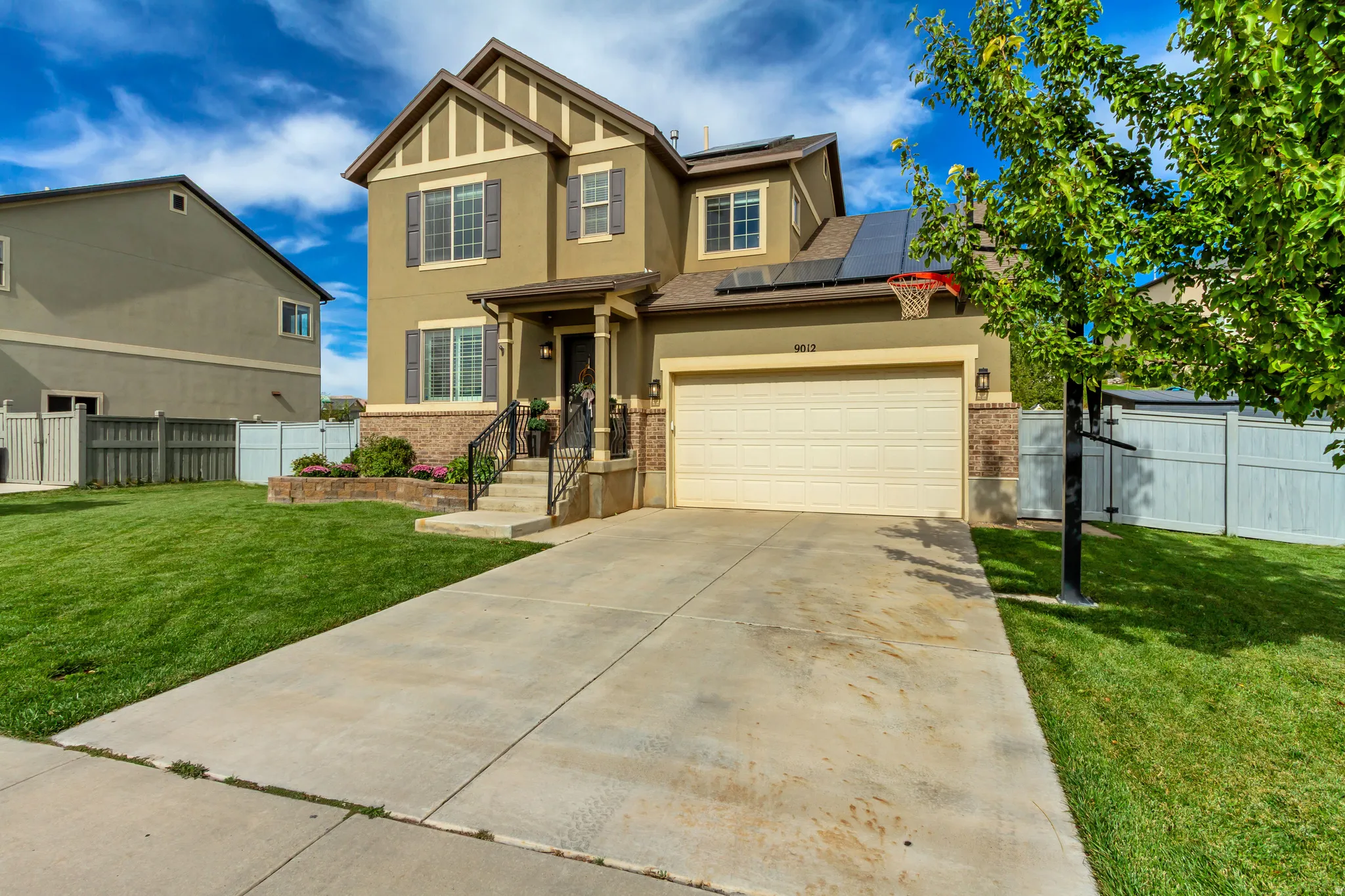Two-story stucco exterior with brick accents, covered front porch, attached garage, and a concrete driveway