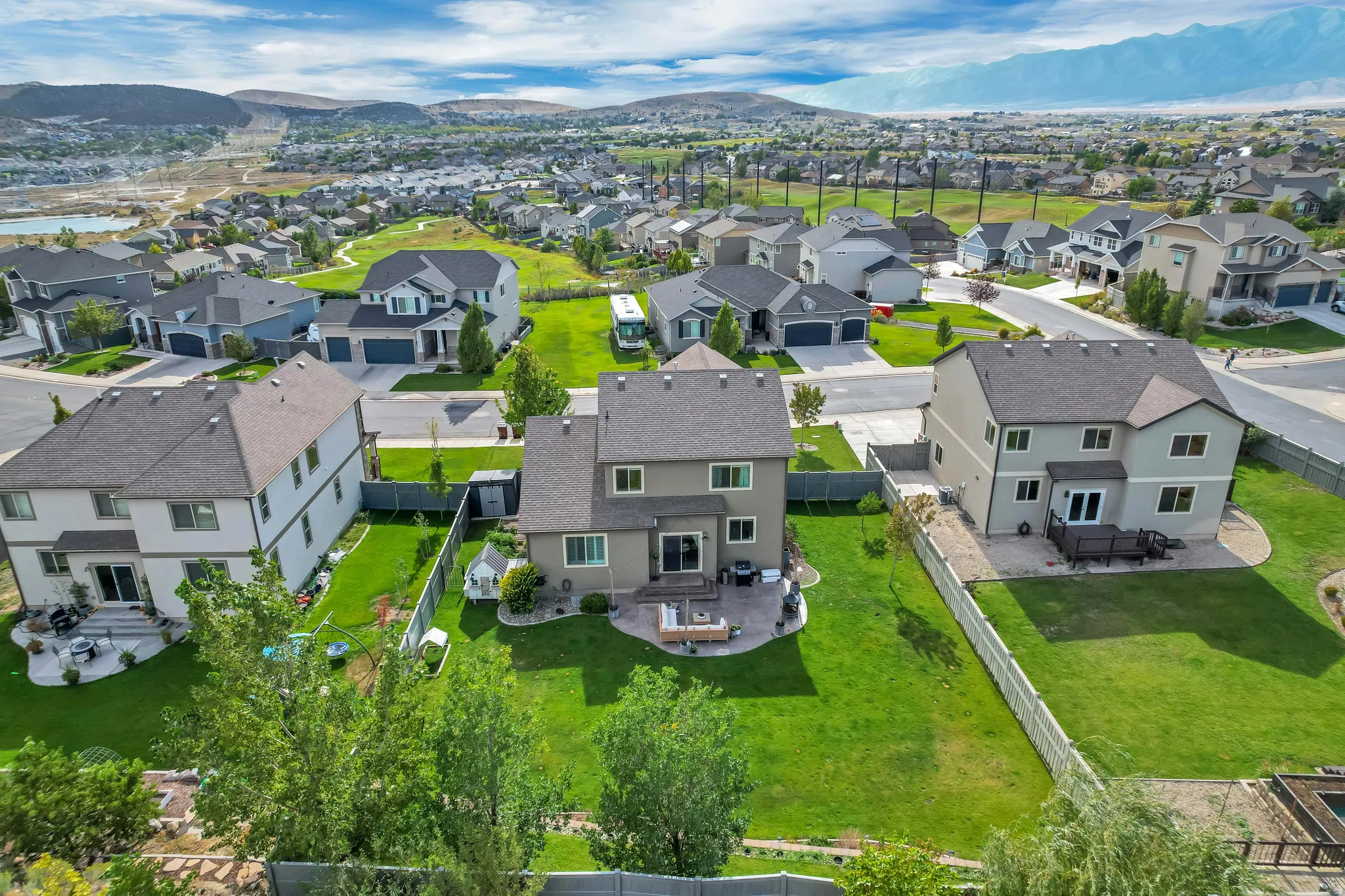 Expansive green lawn, paved patio area, and mature trees