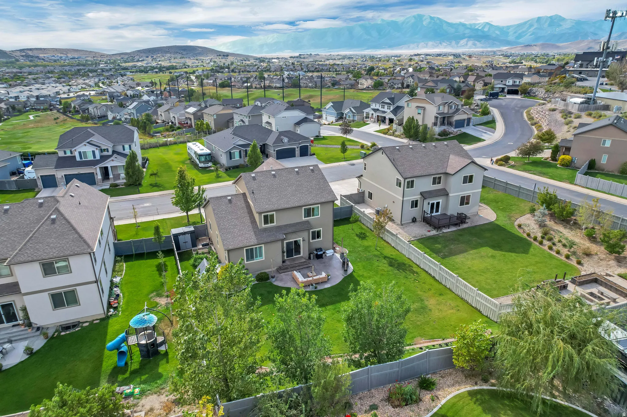 Expansive backyard with a manicured lawn, a paved patio, and a light-toned privacy fence