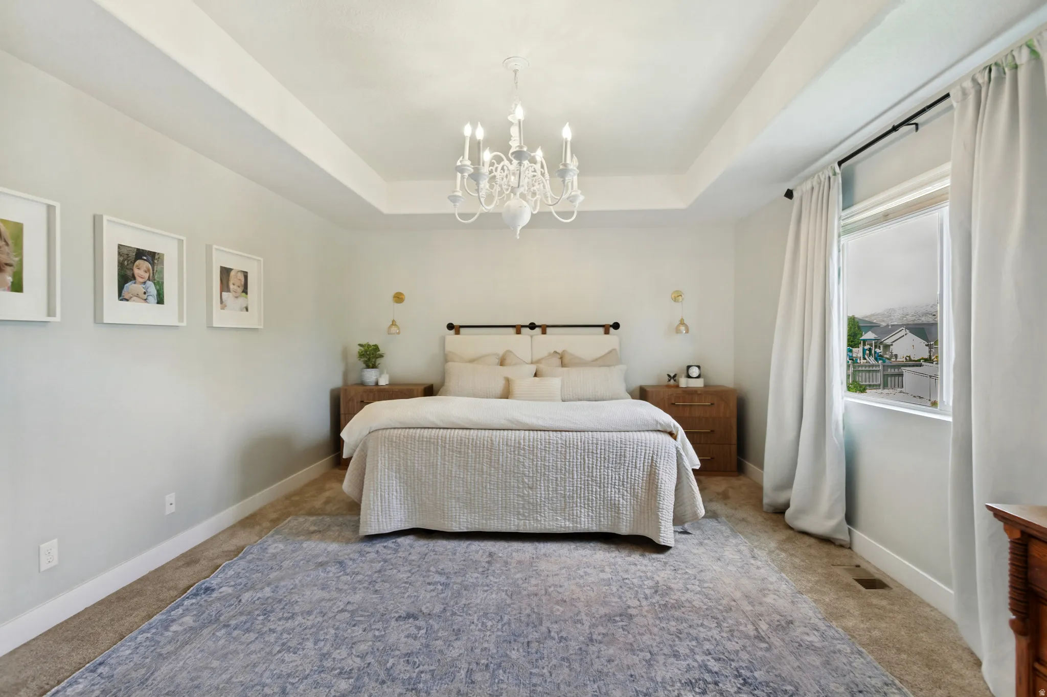 Tray ceiling with a decorative chandelier, neutral wall paint, and carpet flooring