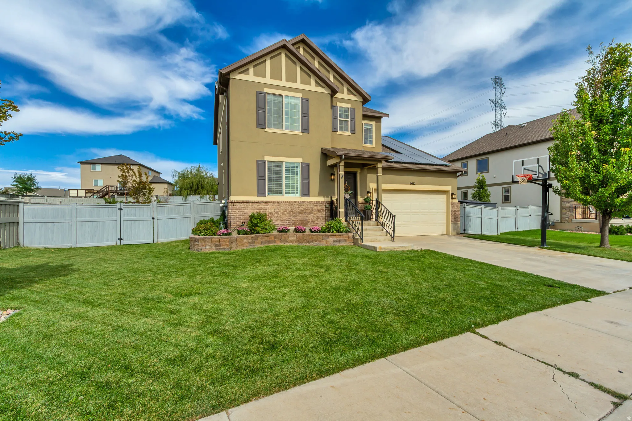 Two-story stucco exterior with stone accents, attached two-car garage, front porch with railing, and a concrete driveway