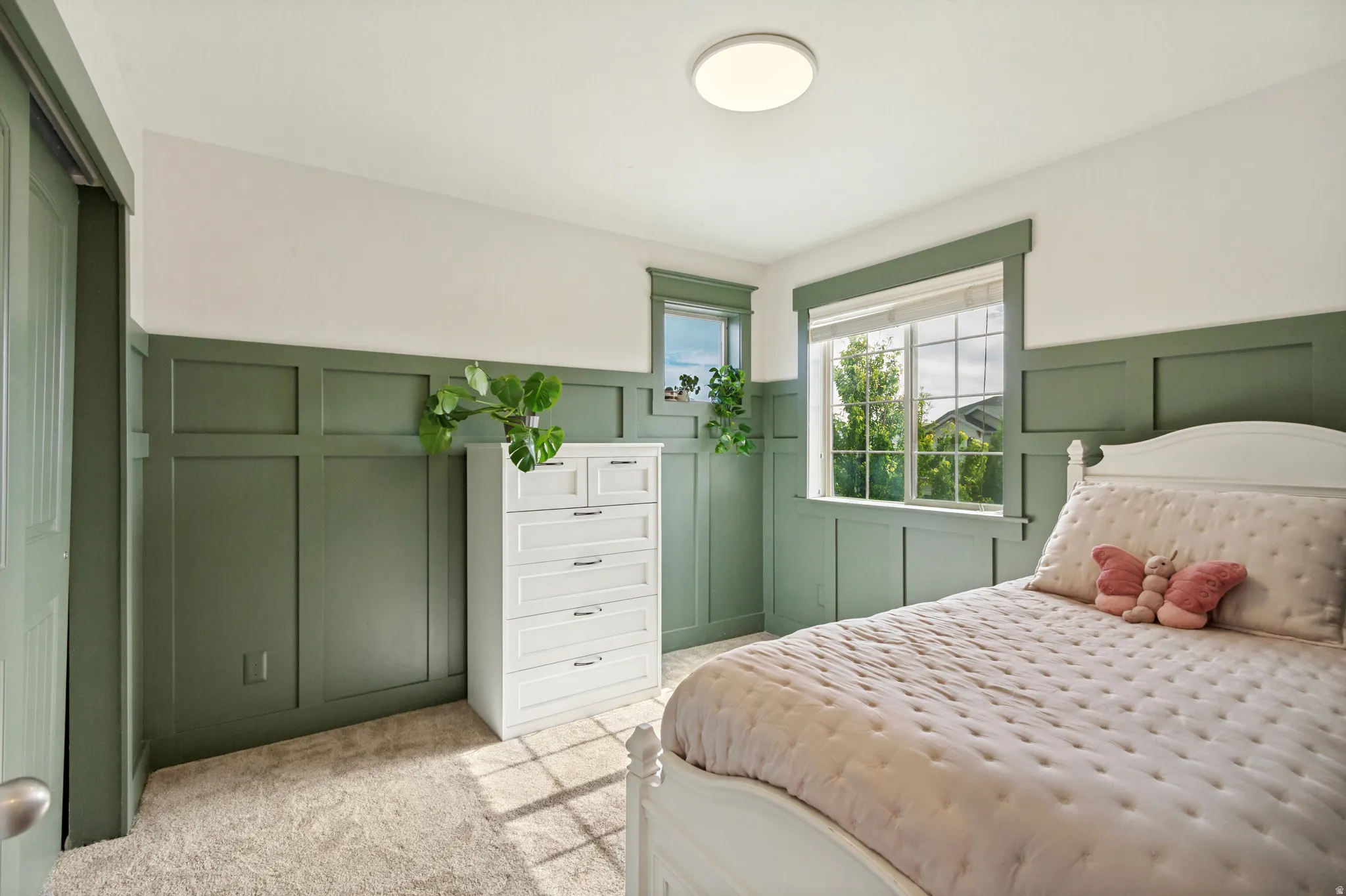 Board and batten wall detailing, two windows with trim, carpet flooring, and a flush mount ceiling light