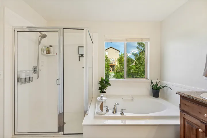 Glass-enclosed shower, built-in soaking tub, and a window with exterior scenery