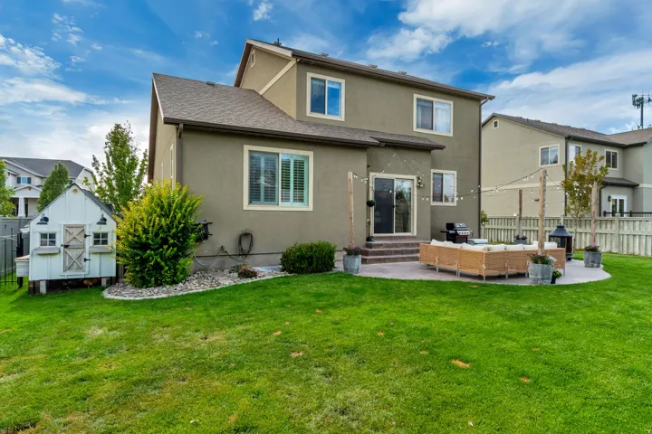 Expansive green lawn with a white shed structure, a built-in paved patio, and sliding glass door access to the interior