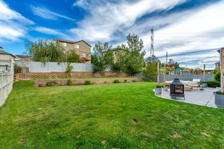 Expansive backyard featuring a manicured lawn, a large paver patio, and retaining walls