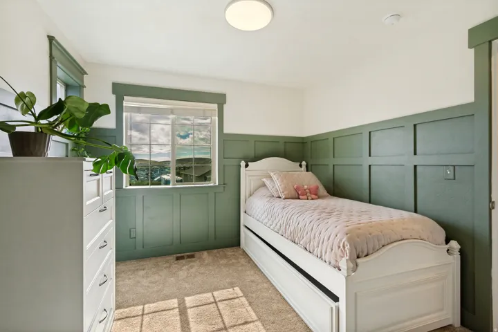 Carpeted room featuring a window with a mountain backdrop, a flush-mount ceiling light, and board and batten wall detailing