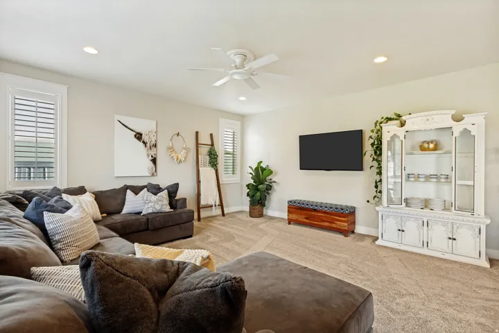 Recessed lighting, ceiling fan, neutral carpet flooring, and white plantation shutters on multiple windows