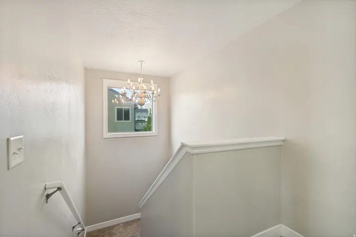 Chandelier lighting, framed window, white trim, and a carpeted staircase
