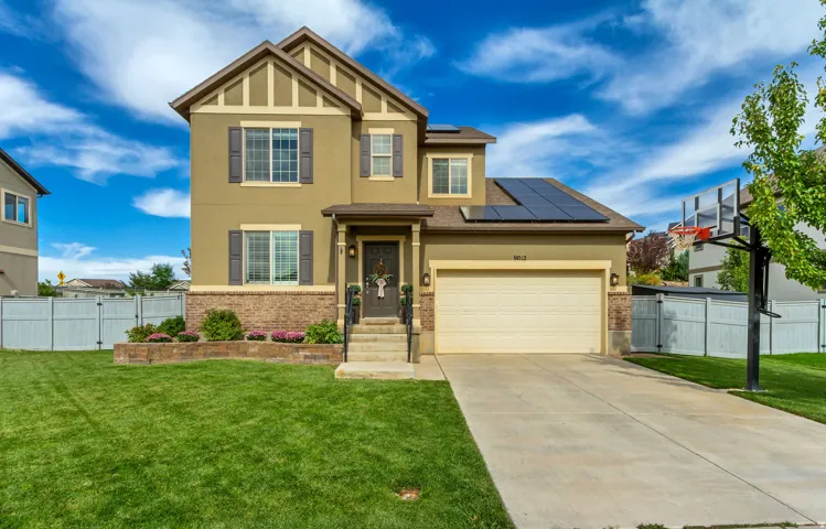 Two-story exterior featuring stucco and brick accents, an integrated two-car garage, and solar panels