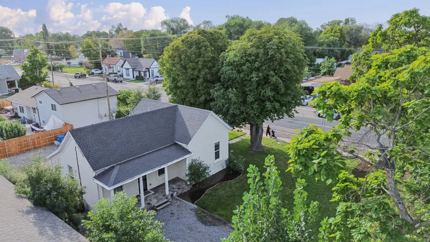 Gable-roof property featuring a covered front porch, dark-toned asphalt shingle roof, and light-toned exterior siding