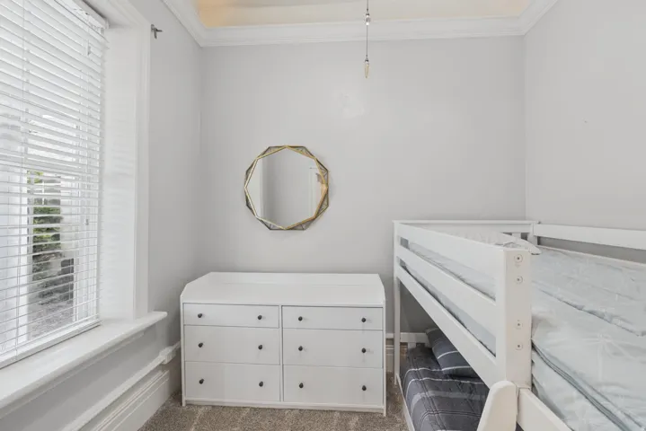 Window with blinds, crown molding, gray wall paint, and carpet flooring