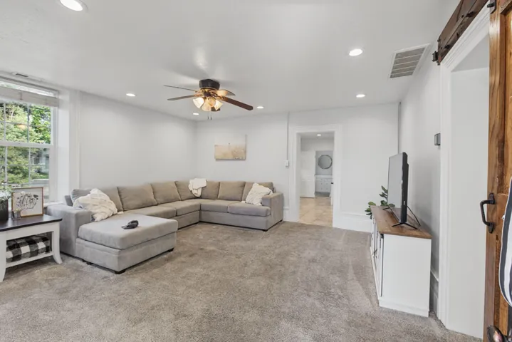 Recessed lighting, ceiling fan, carpeted flooring, and a barn door entry