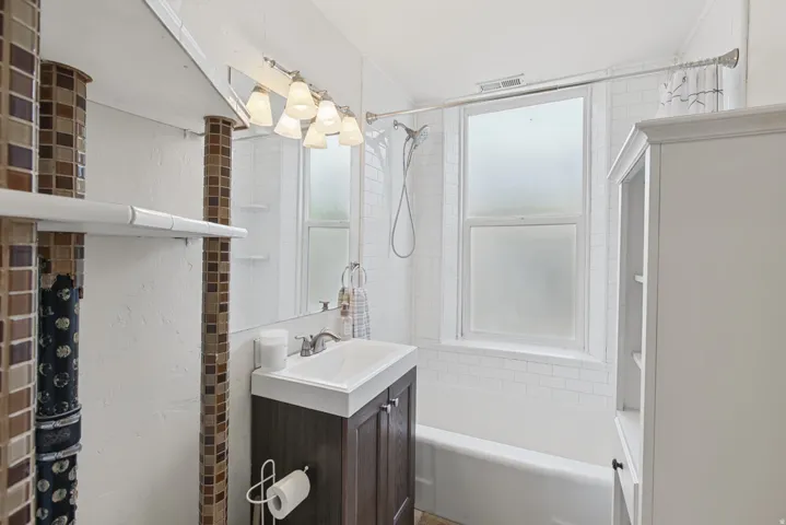 White subway tile surround, built-in bathtub, and a window with obscured glass