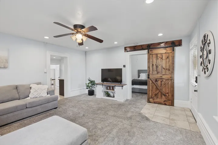Recessed lighting, ceiling fan with light fixture, wood-finish barn door, tile flooring, and carpet flooring