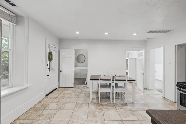 Tiled flooring, recessed lighting, white paneled doors, and a built-in vanity with mirror in a separate room
