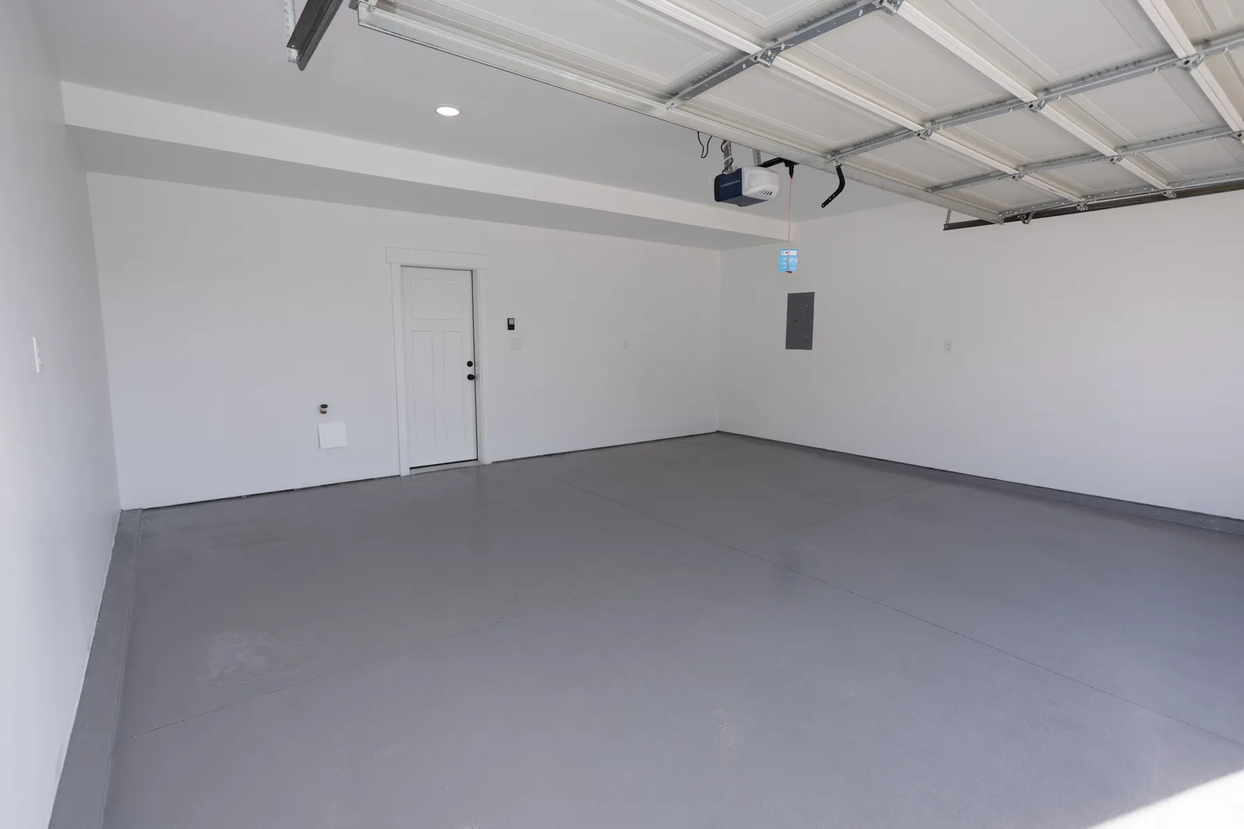 Spacious garage featuring a durable coated concrete floor, recessed lighting, and an overhead garage door opener