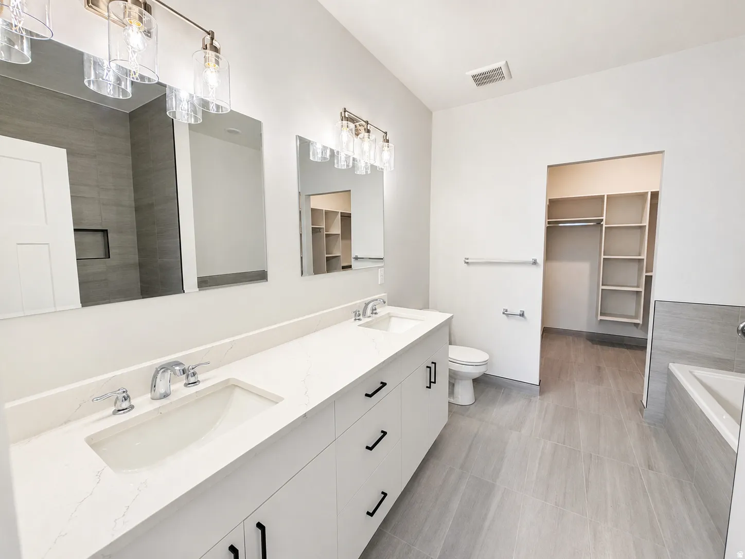 Dual vanity with white cabinetry, quartz-style countertop, and polished chrome fixtures