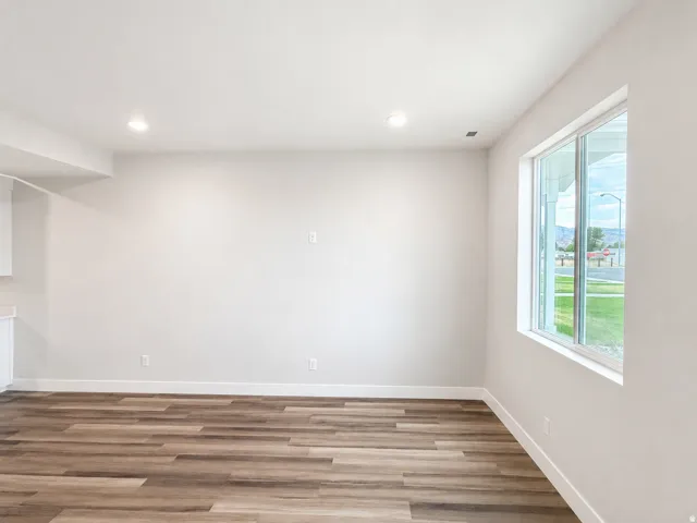 Recessed lighting, wood-finish flooring, white trim, and a large window