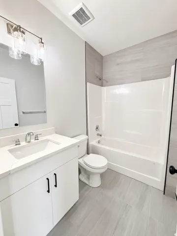 White vanity with a single basin sink and stone countertop