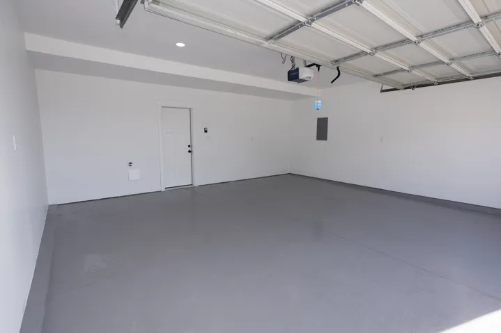 Spacious garage featuring a durable coated concrete floor, recessed lighting, and an overhead garage door opener