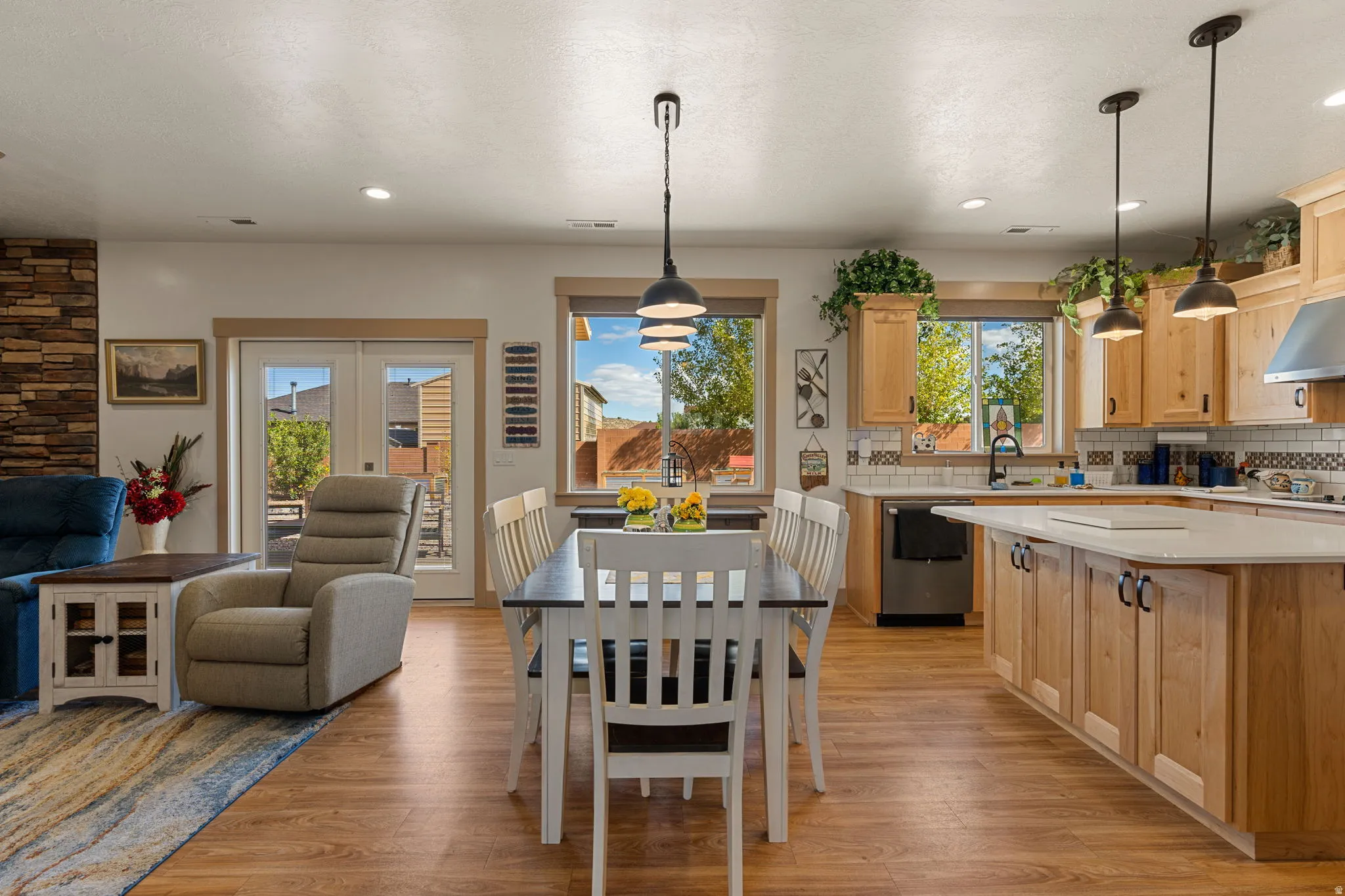 Wood-finish flooring throughout, kitchen with light-toned cabinetry, stainless steel appliances, and a central island with a white countertop
