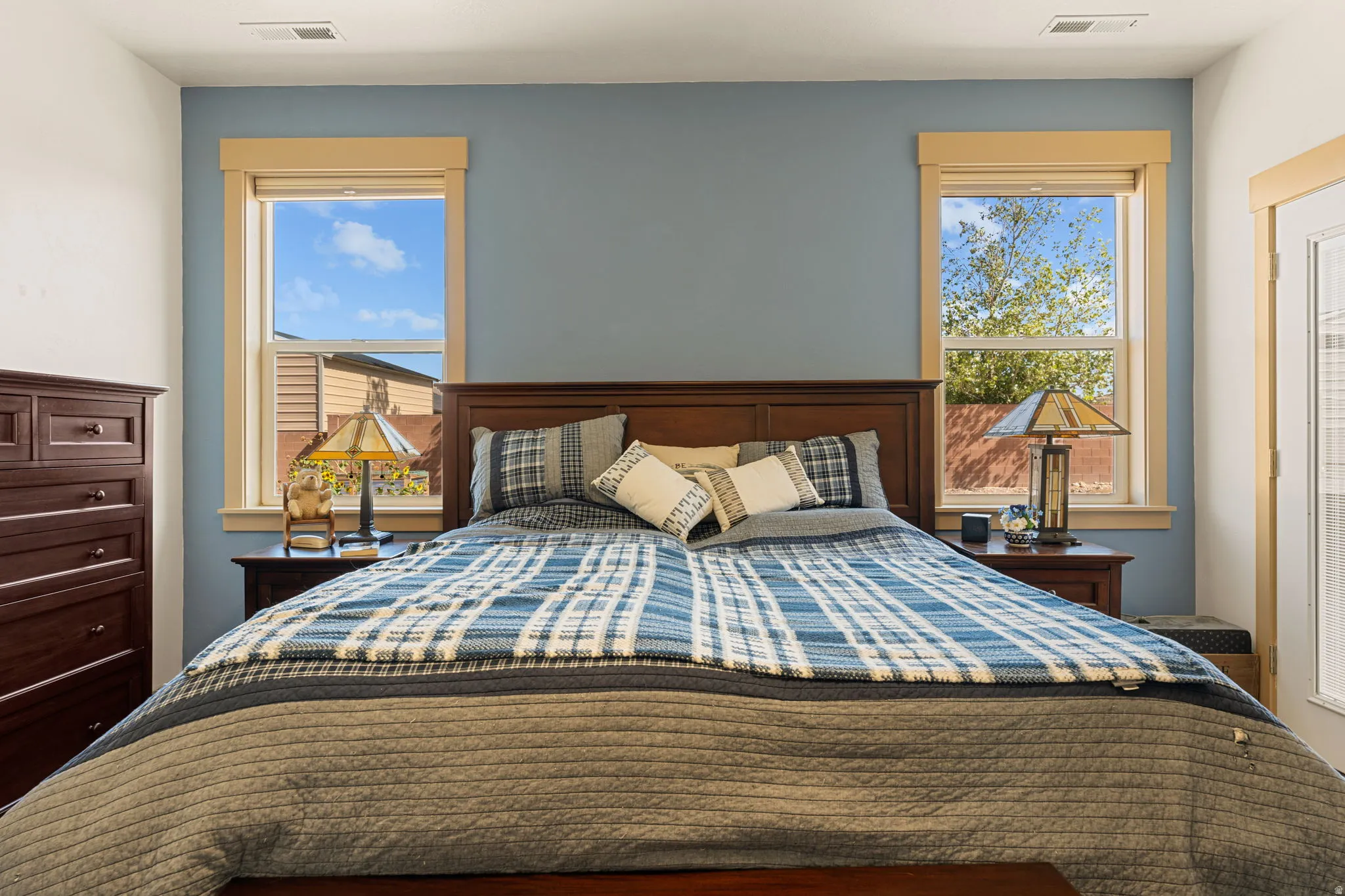 Accent wall with a soft blue finish, framed by two windows featuring light-toned trim, and a white interior door with integrated blinds