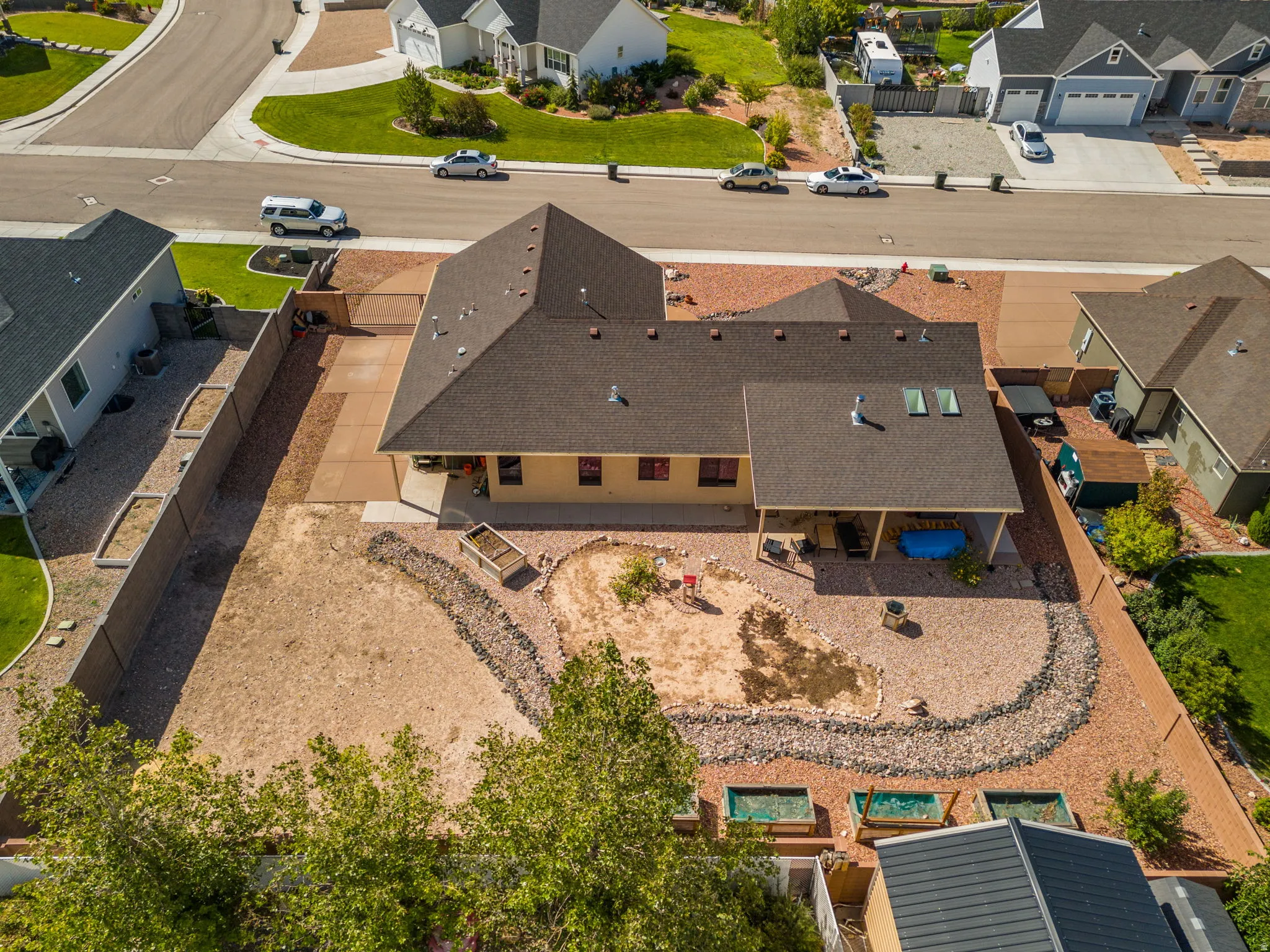 Expansive property featuring a covered patio, skylights, and a gravel-landscaped yard with raised planting beds