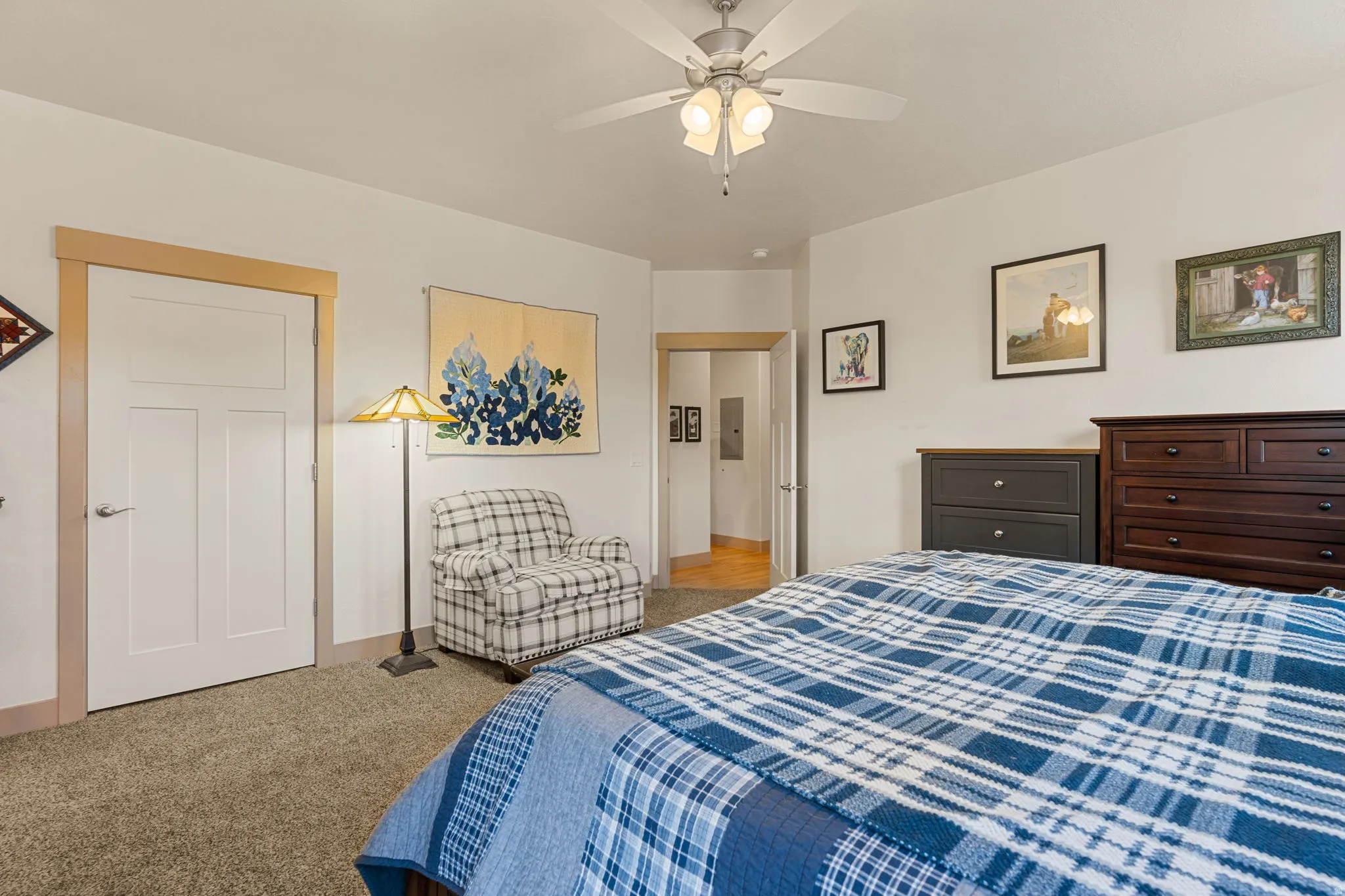 Carpeted flooring, white walls, white paneled door with light wood trim, and a ceiling fan with integrated lighting