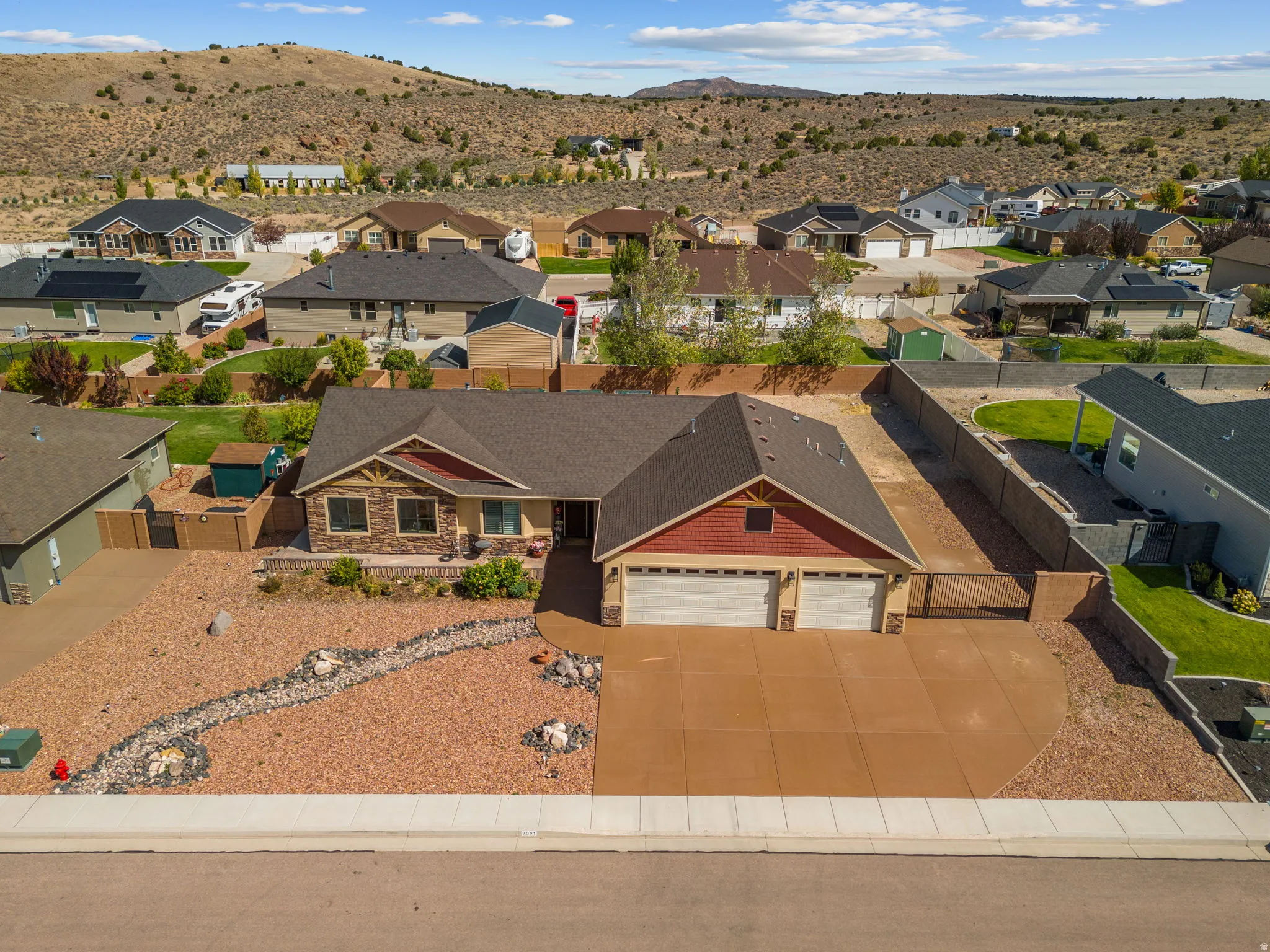 Single-story residence featuring a two-car garage, stone and shingle exterior accents, and a front yard with decorative rock landscaping