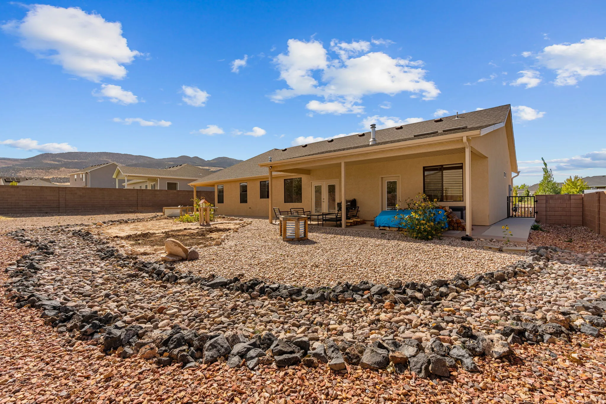 Rear exterior featuring a covered patio, stucco finish, multiple windows, and a gravel landscape