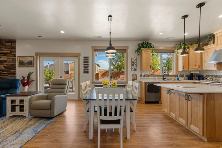 Wood-finish flooring throughout, kitchen with light-toned cabinetry, stainless steel appliances, and a central island with a white countertop