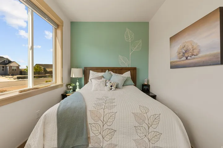Wood-finish headboard, window with street view, light-colored walls, and accent wall with leaf motif