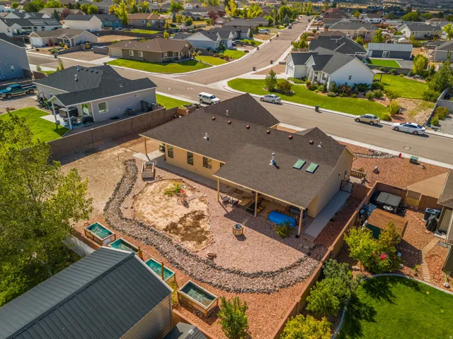Expansive backyard featuring a covered patio, skylights, and a rock-lined landscaping feature
