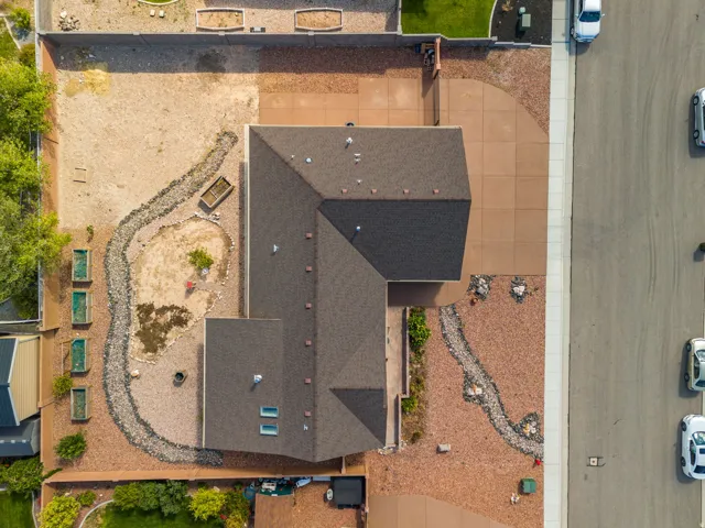 Expansive property featuring a dark shingle roof, a large concrete driveway, and rock landscaping