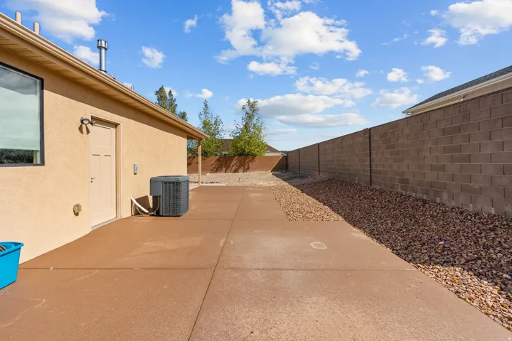 Exterior stucco finish, concrete patio, full-height privacy wall, and integrated HVAC unit