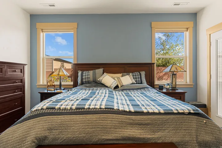 Accent wall with a soft blue finish, framed by two windows featuring light-toned trim, and a white interior door with integrated blinds