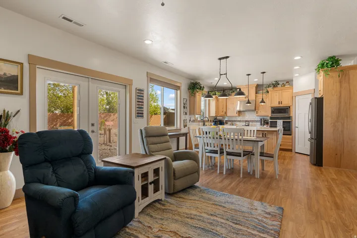 Open-concept living space with wood-finish flooring, recessed lighting, and ample natural light from windows and glass French doors