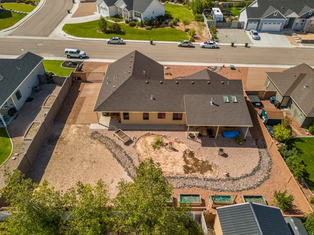 Expansive property featuring a covered patio, skylights, and a gravel-landscaped yard with raised planting beds