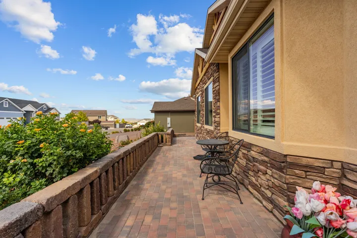 Patio featuring a paver surface, stone-clad exterior, stucco finish, and a retaining wall