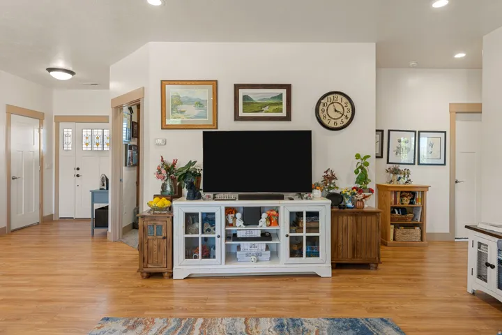 Wood-finish flooring throughout, recessed lighting, and a white interior door with decorative glass panels