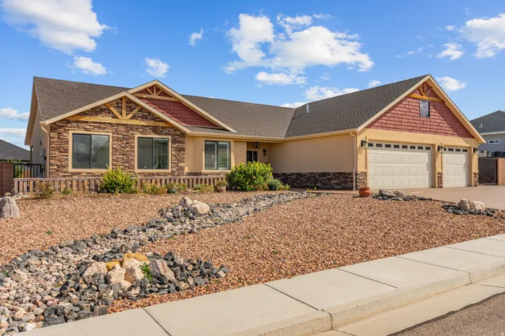 Stucco and stone facade with gabled roof lines, two-car garage, and xeriscaped front yard
